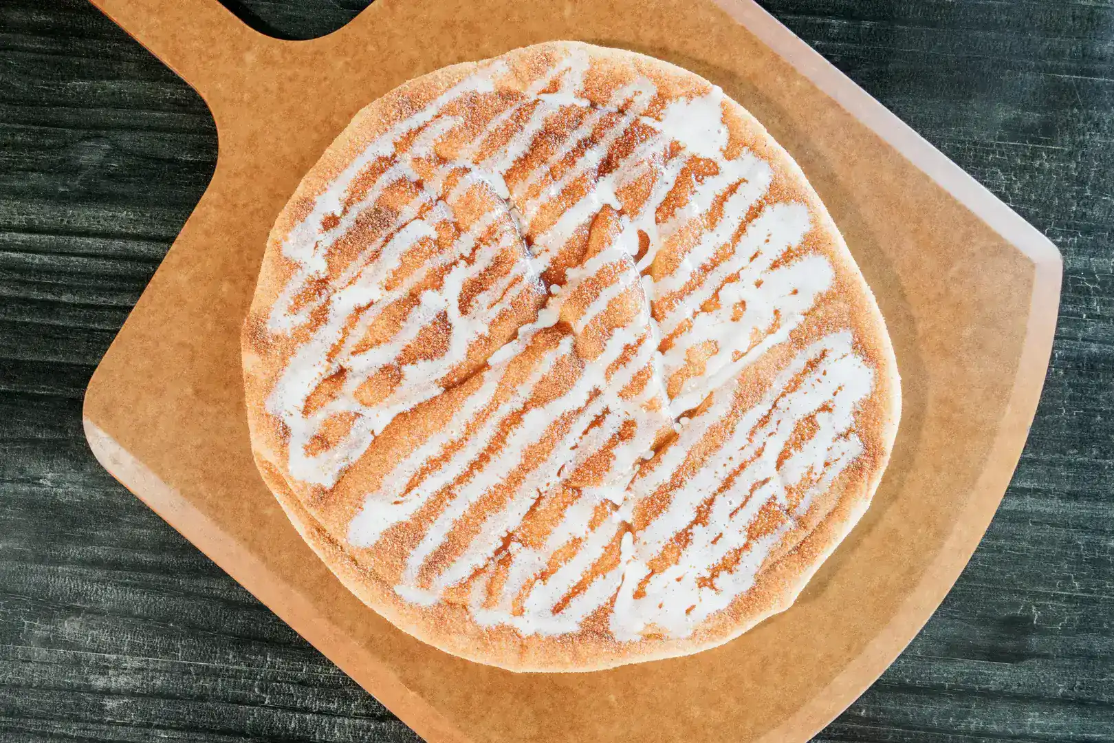 Cinna-Stix 37 Close-up of a Sicilian pizza with white drizzle on a brown paper.